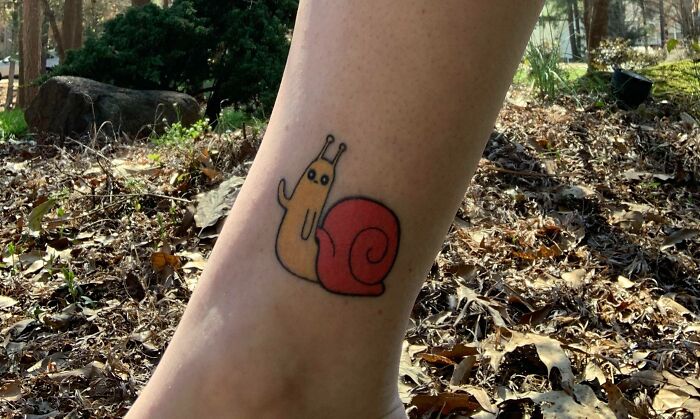 Cartoon tattoo of a snail inspired by favorite animated shows on a person's leg.