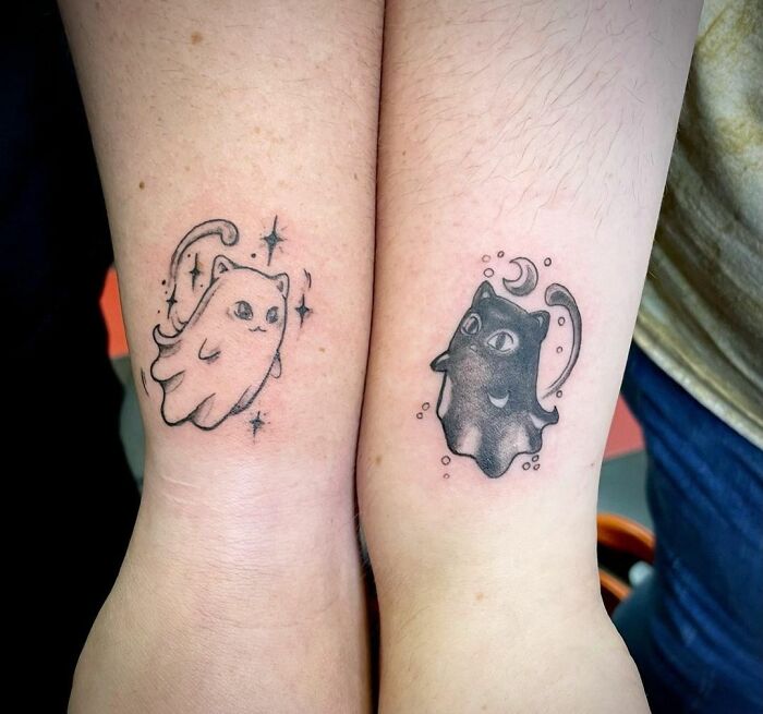 Matching cat tattoos on arms symbolizing friendship.