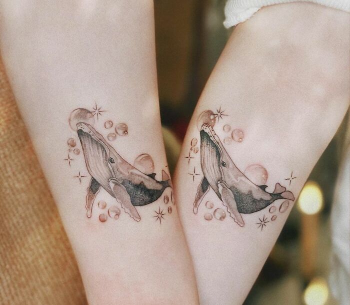 Matching whale tattoos on two arms symbolize deep friendship and connection.