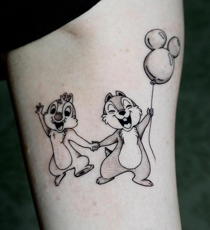Cartoon tattoos of two cheerful chipmunks Chip And Dale holding hands, with one holding a balloon, on an arm.