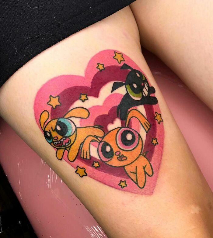Colorful cartoon tattoo of cute characters Blossom, Bubbles and Buttercup in a heart design on skin.