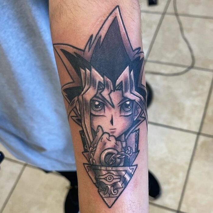 Cartoon tattoo of an anime character on a forearm, showcasing detailed line art and shading.