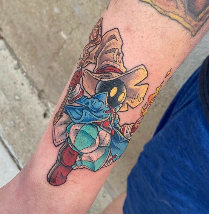 Colorful Final Fantasy video game tattoo of a wizard character with a blue cloak and hat on forearm.