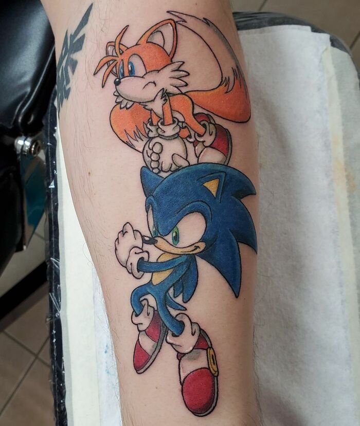 Video game tattoo featuring a colorful design of two iconic game characters on an arm.