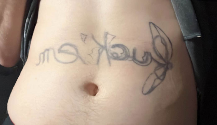 Tattoo mistake on stomach showing reversed lettering and design, indicating a regrettable choice.