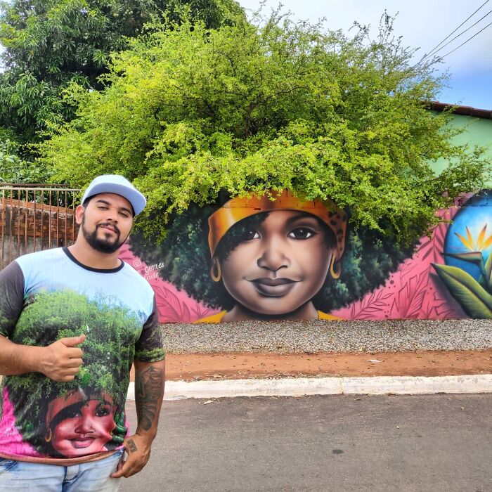 Street Artist Continues To Paint Portraits On Walls Next To Trees That Double As Hair