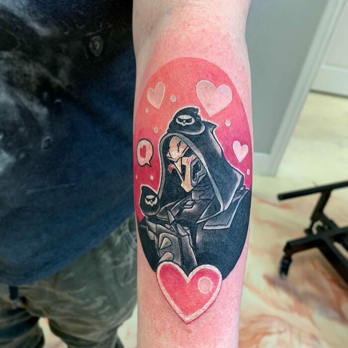 Tattoo of a character from Overwatch video game with hearts on an arm, ideal for hardcore gamers.