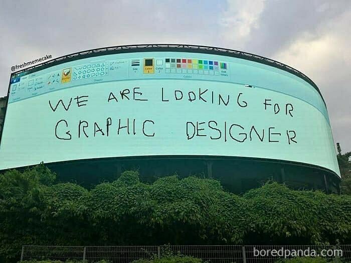 Funny graphic design meme with message "We are looking for graphic designer" handwritten on a digital billboard.