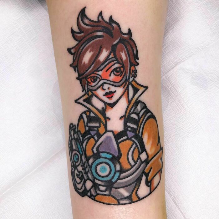 Overwatch video game character tattoo in vibrant colors on a forearm.