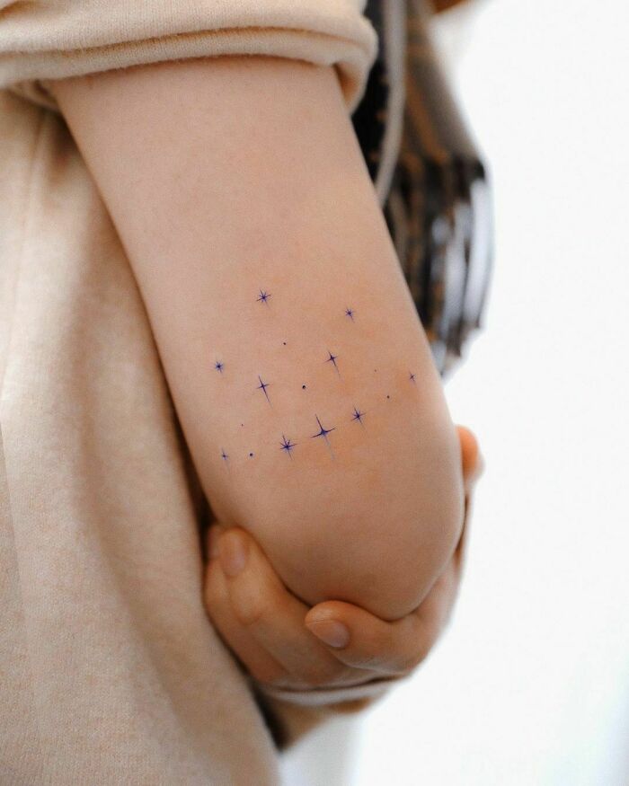 Minimalist star pattern tattoo on elbow.