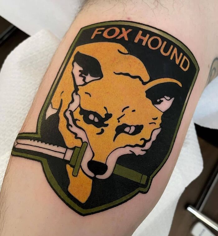 Metal Gear video game tattoo featuring the Fox Hound logo, showcasing a fox with a knife in its mouth.