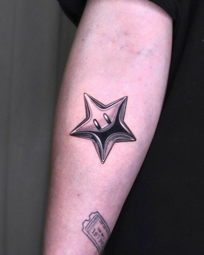 Star-shaped video game tattoo on arm, perfect for hardcore gamers.