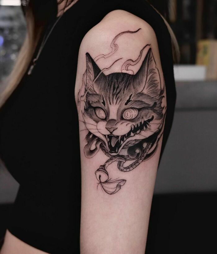 Gothic tattoo of a snarling cat with smoke details on a person's arm.