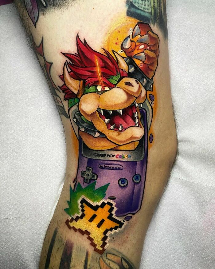 Tattoo of a colorful Nintendo video game character emerging from a Game Boy on a gamer’s leg.