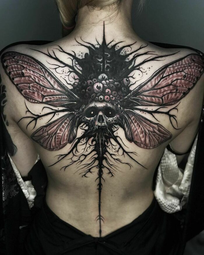 Gothic tattoo featuring an intricate skull and wing design on a person's back.