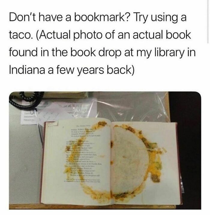 Photo of a book used as a taco-shaped bookmark, showing food stains on the open pages in a library setting.