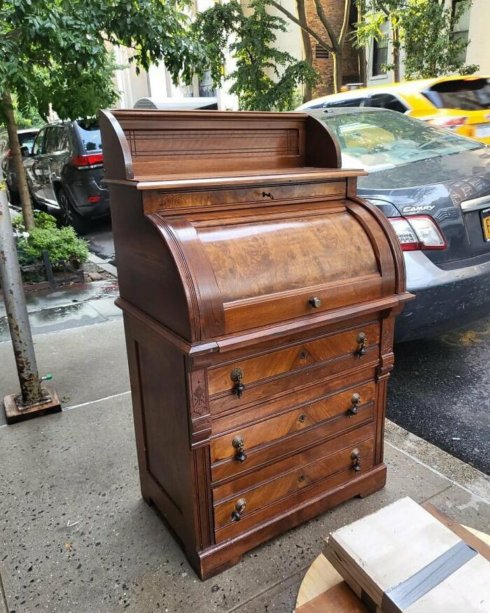 Antique wooden roll-top desk left on NYC sidewalk, an example of real treasures people threw out in the city.