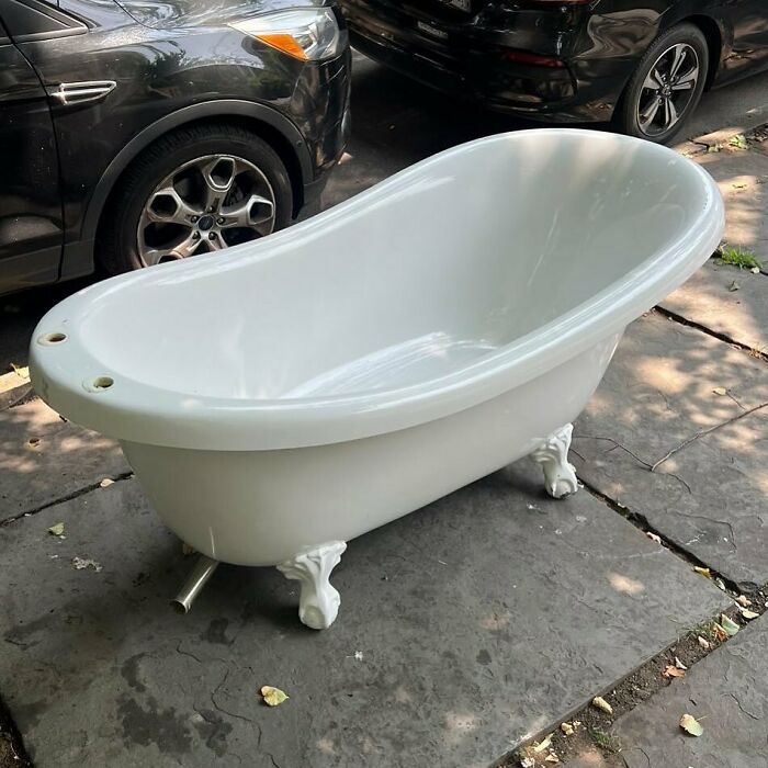 Clawfoot bathtub discarded on a NYC sidewalk, an example of real treasures thrown out in the city streets.