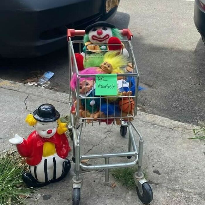 Shopping cart filled with vintage clown and troll dolls left on NYC sidewalk, a true stoop and stare treasure found.