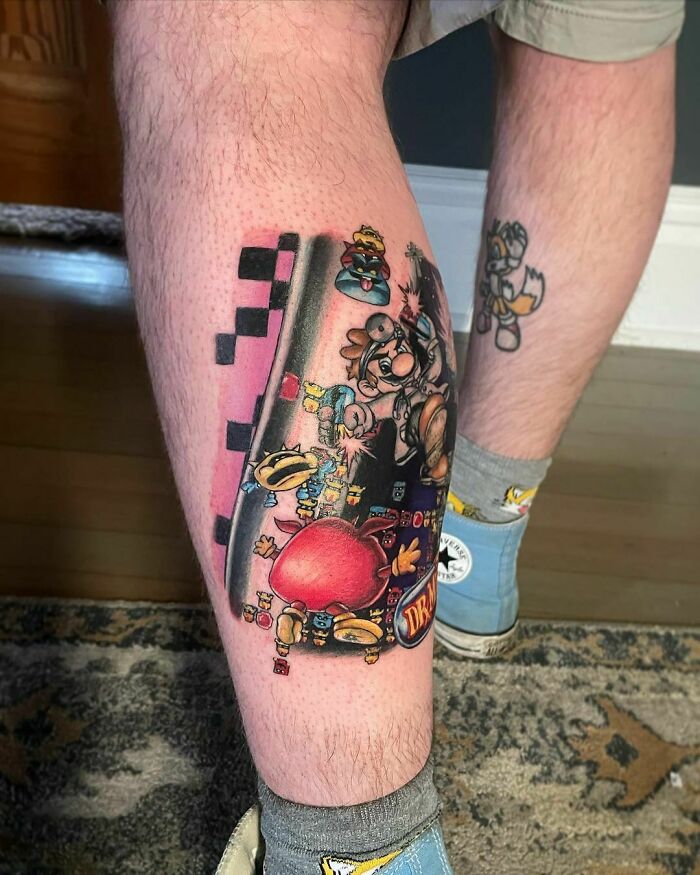 Tattoo depicting vibrant video game characters on a person's leg, showcasing hardcore gamer art.