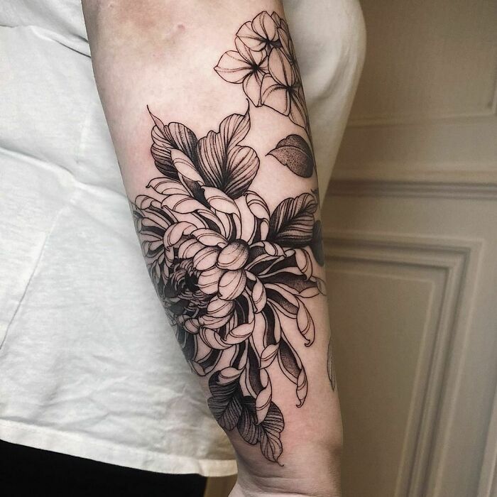 A detailed gothic tattoo of a floral design on a forearm, showcasing intricate linework and shading.
