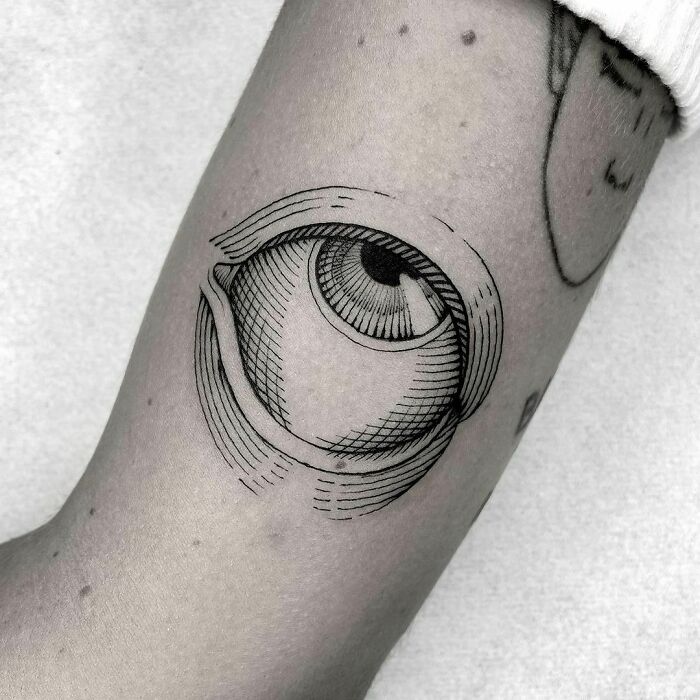 Gothic tattoo of a stylized eye on an arm, showcasing intricate line work and shading.