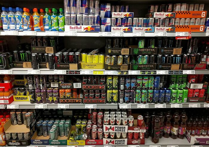 Shelves stocked with various energy drinks including Red Bull, Monster, Rockstar, and others in a store aisle display.