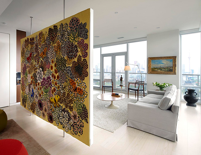 A large floating room divider is held in place with metal rods, with one side covered in a tapestry with plants, flowers, and butterflies A large floating room divider is held in place with metal rods, with one side covered in a tapestry with plants, flowers, and butterflies