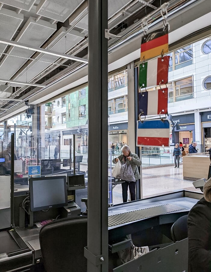 In This Grocery Store, Cashiers Hangs Up Flags At Their Registers To Indicate The Languages They Speak