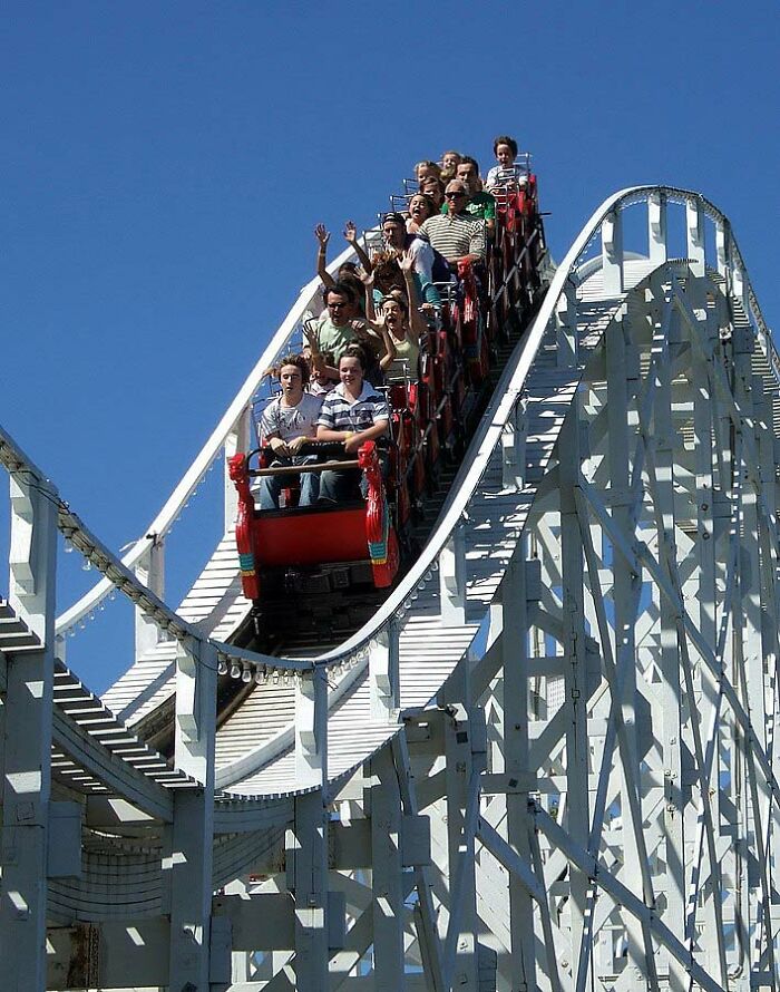 Riders on the Scenic Railway at Luna Park Melbourne enjoying a thrilling moment, perfect for sharing useless facts.