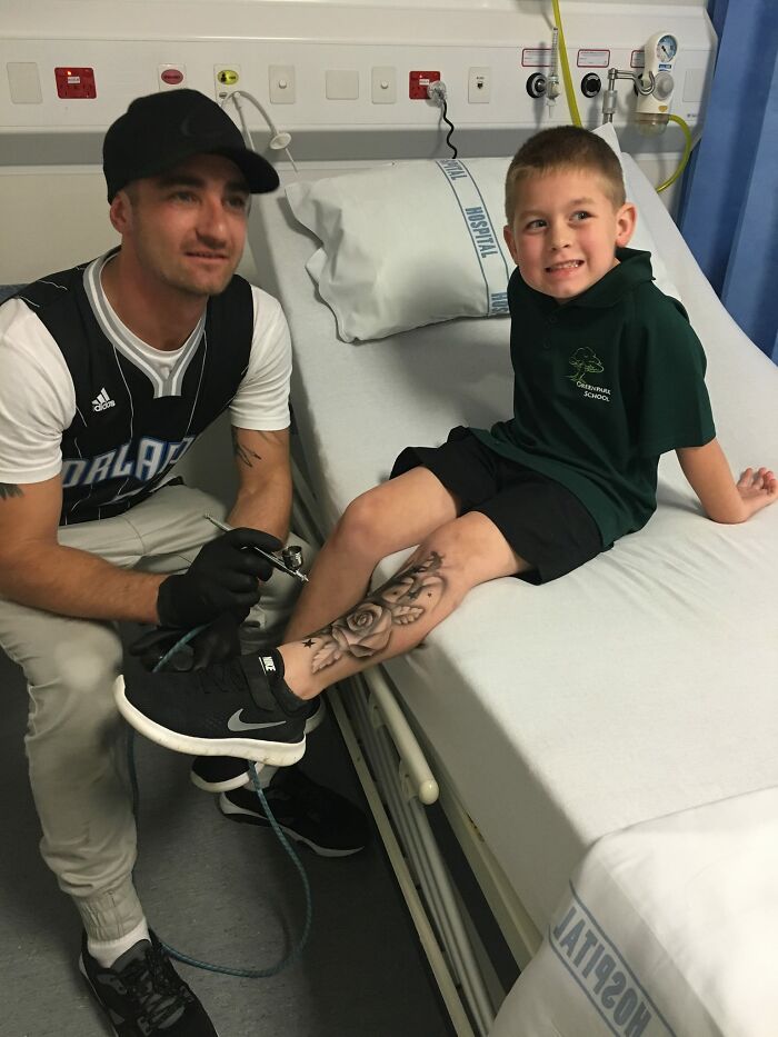 Artist giving hospitalized child a spray-on tattoo in a hospital room, brightening the child's day.