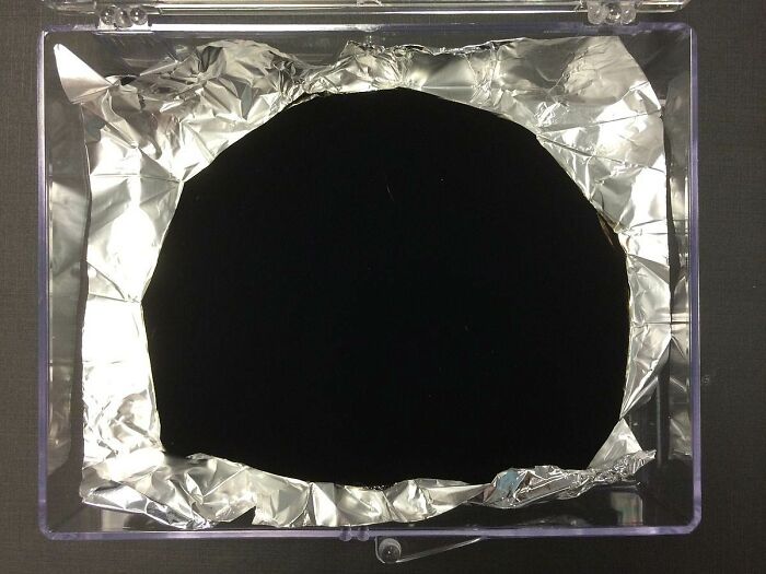 Vantablack coating on aluminum foil absorbing light and removing all visible texture, a fascinating useless fact to impress friends.