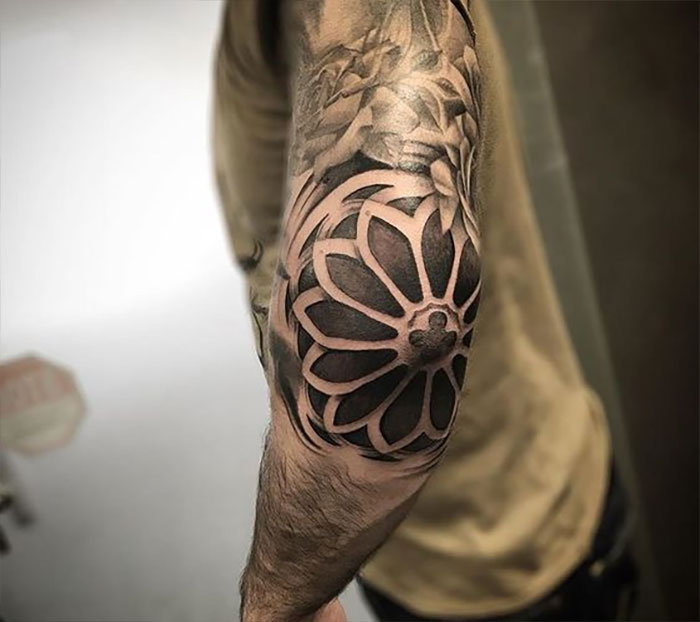 Stylish geometric flower elbow tattoo with intricate shading on a man's arm, showcasing unique tattoo ideas.