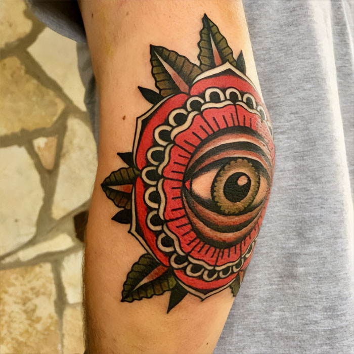 Colorful eye and floral design as an elbow tattoo, showcasing a unique and artistic style.