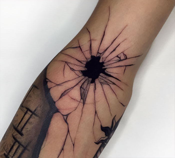 Elbow tattoo featuring a realistic c*****d design with a black center, creating a striking visual illusion.