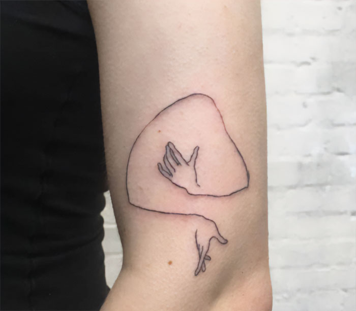 Minimalist elbow tattoo featuring a hand design, showcasing unique tattoo ideas.