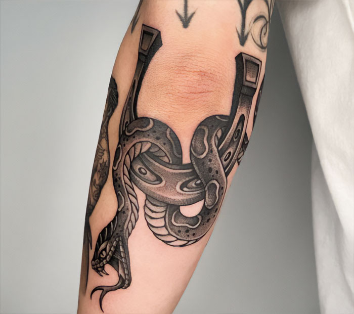 Snake-themed elbow tattoo with intricate black and gray details showcasing dynamic design.