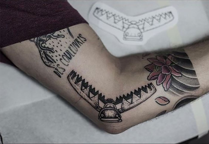 Elbow tattoo of a bear trap design with additional floral details, showcasing unique ink art.