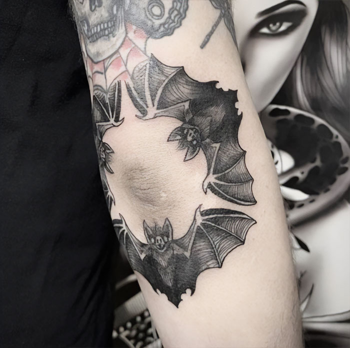 Elbow tattoo featuring bats arranged in a circular pattern.