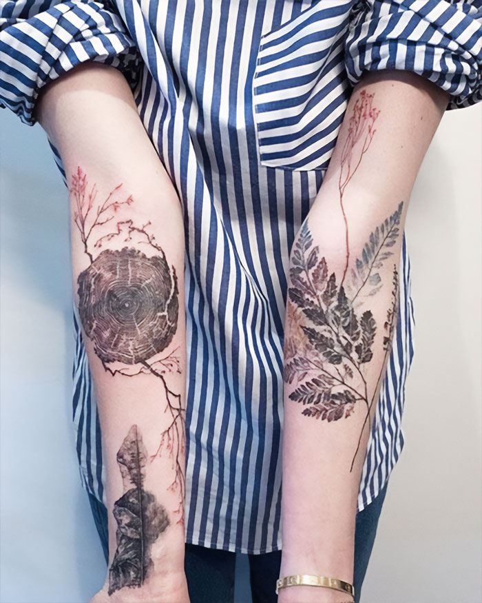 Abstract tree and branch elbow tattoos on forearms, showcasing intricate nature designs.