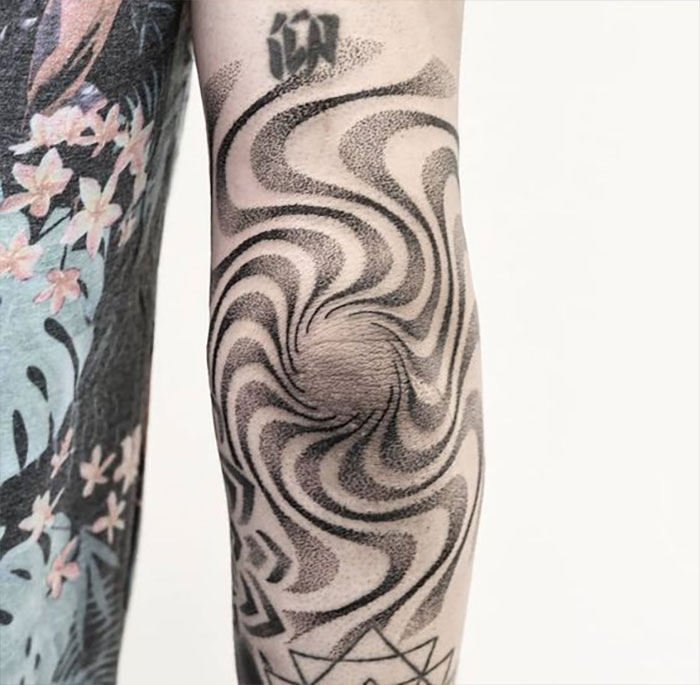 Abstract black and gray swirling elbow tattoo design showcasing dazzling art.
