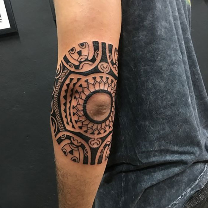 Intricate geometric elbow tattoo design on a person's arm, featuring bold patterns and detailed linework.