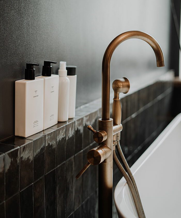 Brass Tap And Cleaining Supplies In Bathroom Near A White Bathtub Brass Tap And Cleaining Supplies In Bathroom Near A White Bathtub