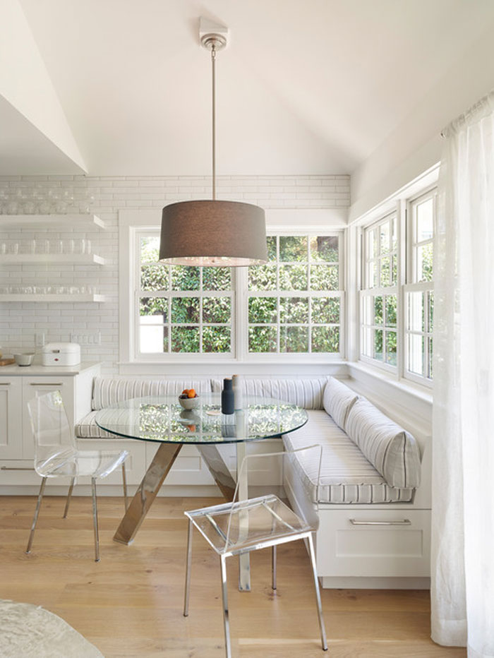 White interior cozy breakfast nook with a glass table and chairs and storage space White interior cozy breakfast nook with a glass table and chairs and storage space