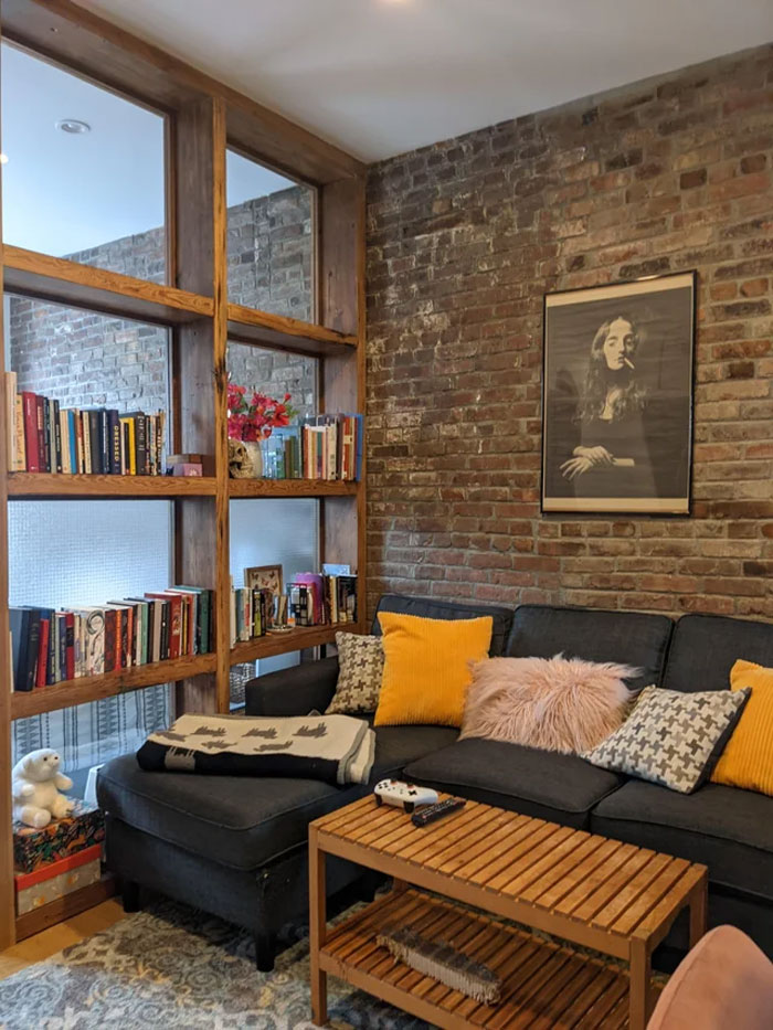 Shelves with books and couch in a room space with rustic brick wall Shelves with books and couch in a room space with rustic brick wall