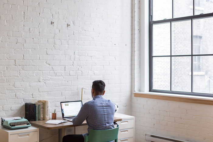 Man working in a white brick wall room Man working in a white brick wall room