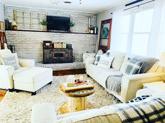 White wash brick wall room with sofas and armchair, fireplace and carpet on the floor White wash brick wall room with sofas and armchair, fireplace and carpet on the floor