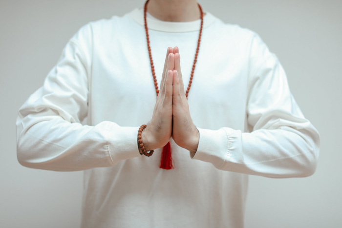 Person in white long sleeve performing Namaste gesture, symbolizing culture diversity and beauty of the world facts.
