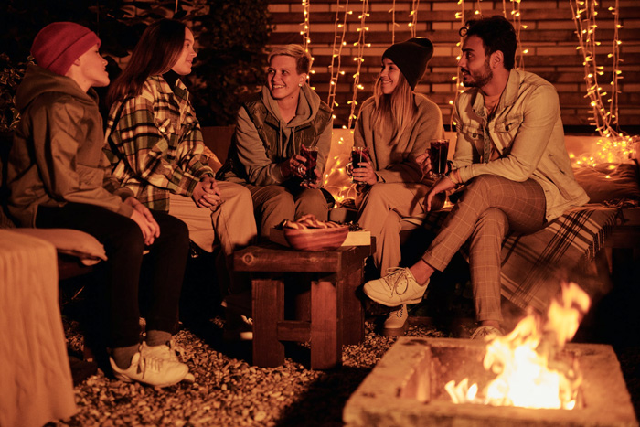 Group of friends enjoying diverse cultural moments sitting around a bonfire at night, reflecting world beauty and unity.