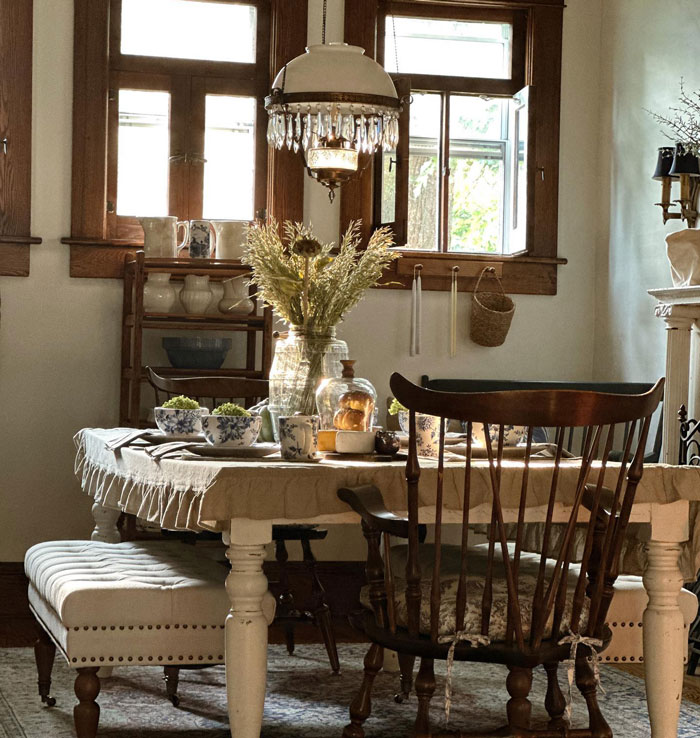 Vintage farmhouse table with white sheet on it chairs cups and flowers Vintage farmhouse table with white sheet on it chairs cups and flowers